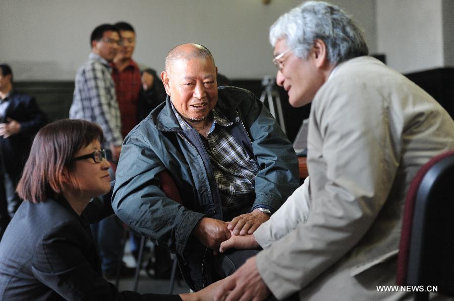 Li Chen (C), a Japanese abandoned chemical weapon victim, talks with Norio Minami (R), a Japanese lawyer, during a hearing event in Harbin, capital of northeast China's Heilongjiang Province, April 29, 2014. 
