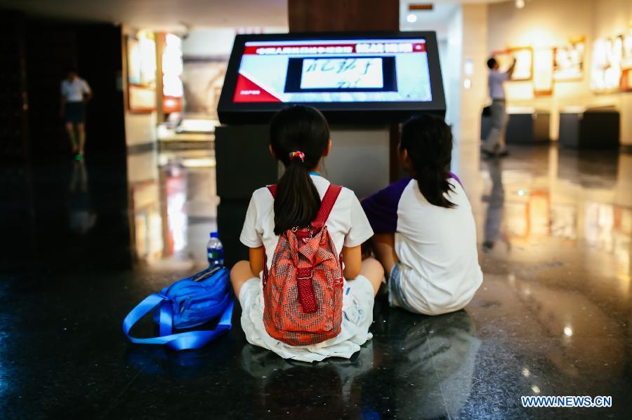 Children watch videos during the 'Great Victory, Historic Contribution' exhibition in Beijing, capital of China, July 14, 2015. 