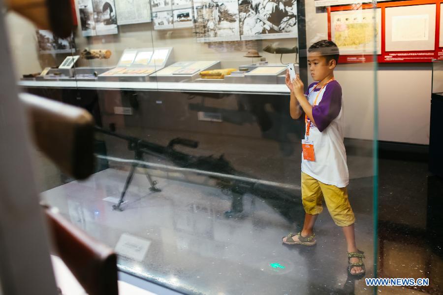 A child uses a cellphone to takes photos of weapons used by Chinese armies during the 'Great Victory, Historic Contribution' exhibition in Beijing, capital of China, July 14, 2015. 