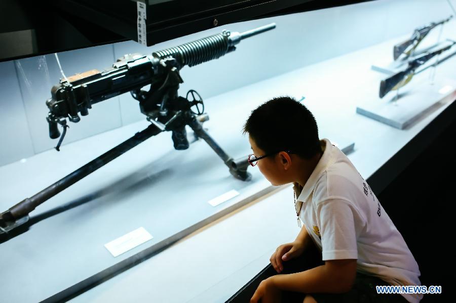 A child views a weapon used by the Japanese army in Northeast China during the 'Great Victory, Historic Contribution' exhibition in Beijing, capital of China, July 14, 2015.