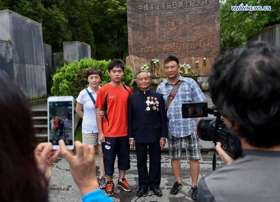 Lu Caiwen (2nd R) poses for a group photo with visitors at Guoshang Graveyard in Tengchong, southwest China's Yunnan Province, July 21, 2015.