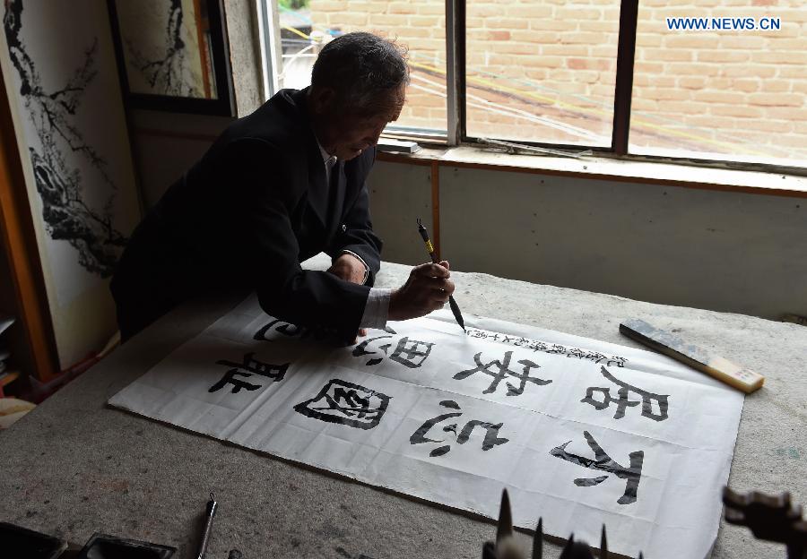 Lu Caiwen practises calligraphy at his home in Tengchong, southwest China's Yunnan Province, July 20, 2015. 