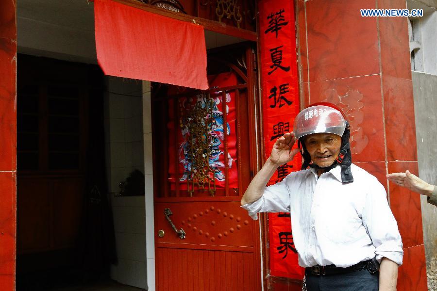 Lu Caiwen wears his armet before he leaves home in Tengchong, southwest China's Yunnan Province, July 20, 2015.