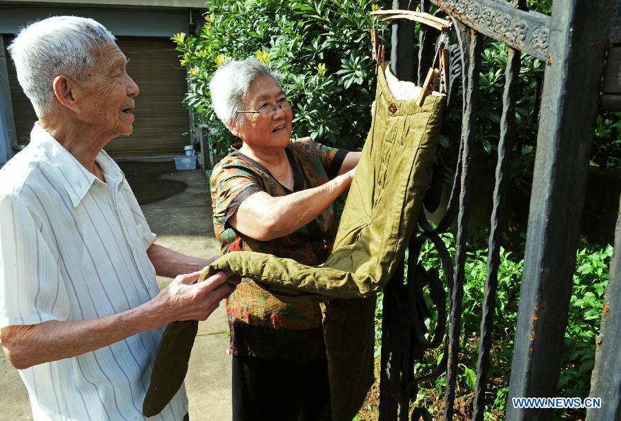 Wang Mingcai and his wife He Xiujuan hang up his 60-year-old cotton-padded trousers at home in Yiwu, east China's Zhejiang Province, July 26, 2015.