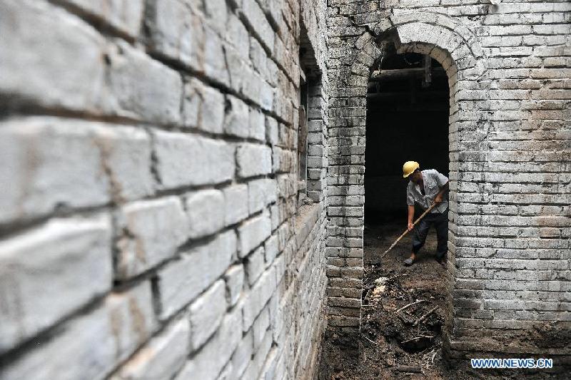 A worker clears rubbish at the site of a former concentration camp in Taiyuan, capital of north China's Shanxi Province, Aug. 3, 2015. 