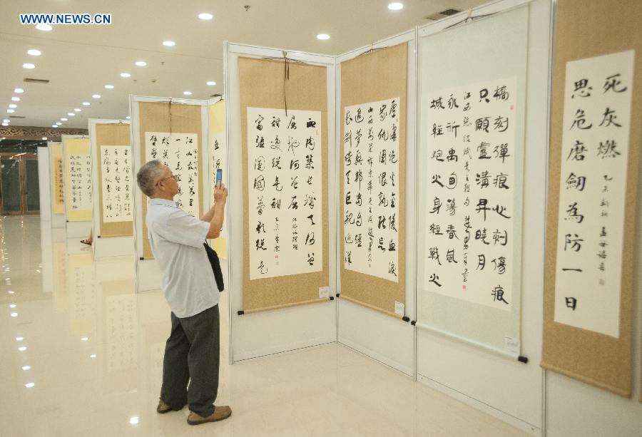 A visitor takes photos of the award-winning works at a calligraphy exhibition in Beijing, capital of China, Aug. 17, 2015. 