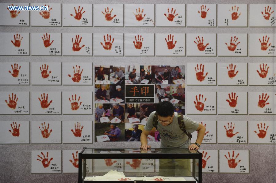 Visitors view handprints of comfort women survivors in an exhibition of photos and real objects at the Hangzhou Library in Hangzhou, capital of east China's Zhejiang Province, Aug. 18, 2015. 