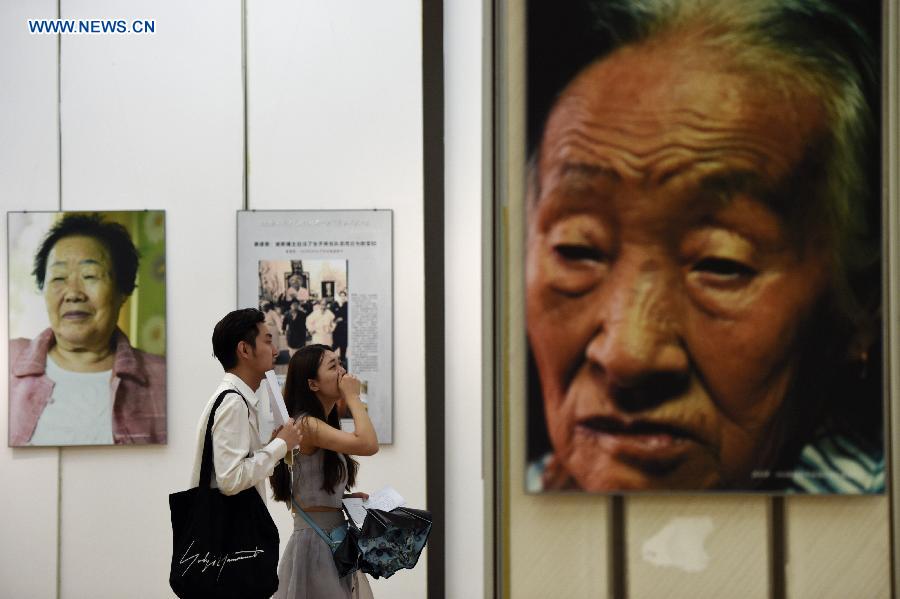 Visitors view portraits and introduction of comfort women survivors in an exhibition of photos and real objects at the Hangzhou Library in Hangzhou, capital of east China's Zhejiang Province, Aug. 18, 2015. 