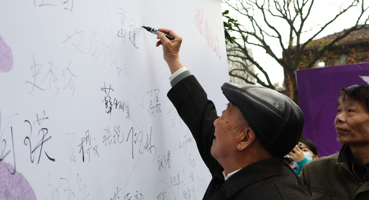 南京大屠杀幸存者葛道荣在和平寄语墙上签名。