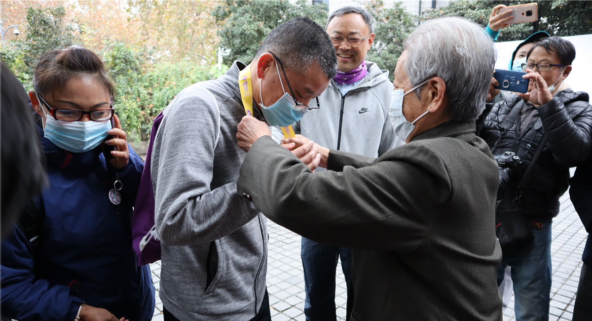 南京大屠杀幸存者艾义英为第一位到达终点的市民陶成发颁发和平纪念牌。